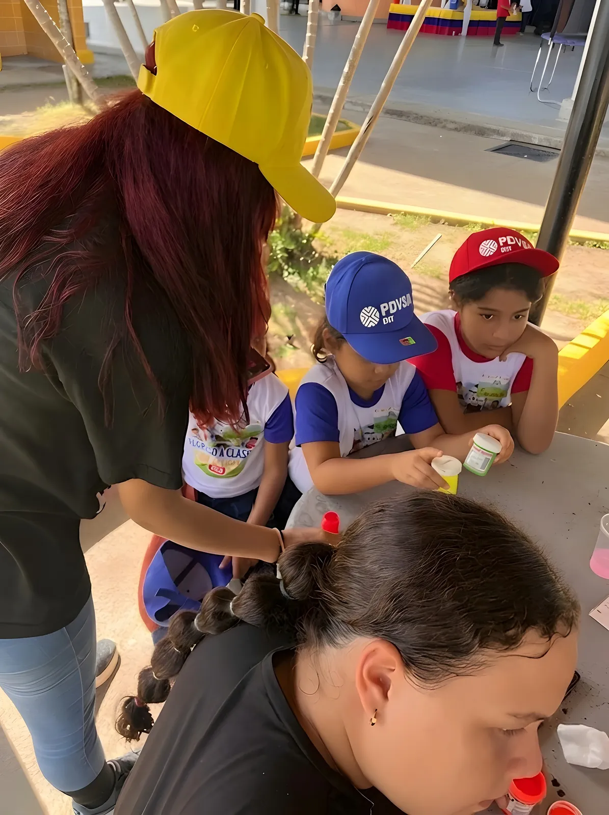 Niños pintan con témperas en una mesa redonda.