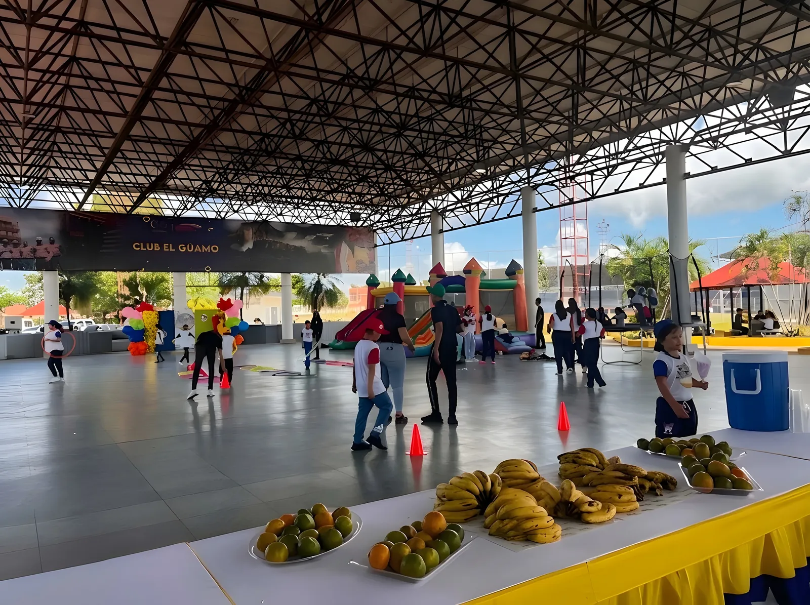 Mesa con bandejas de naranjas, mandarinas y cambures en la cancha del evento.
